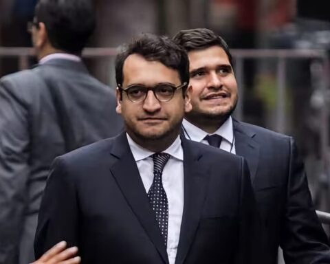 Hombre de traje y lentes caminando en entorno urbano
